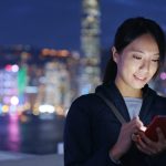 woman-using-mobile-phone-at-night-in-front-of-a-lit-up-city-scape-scaled.jpg