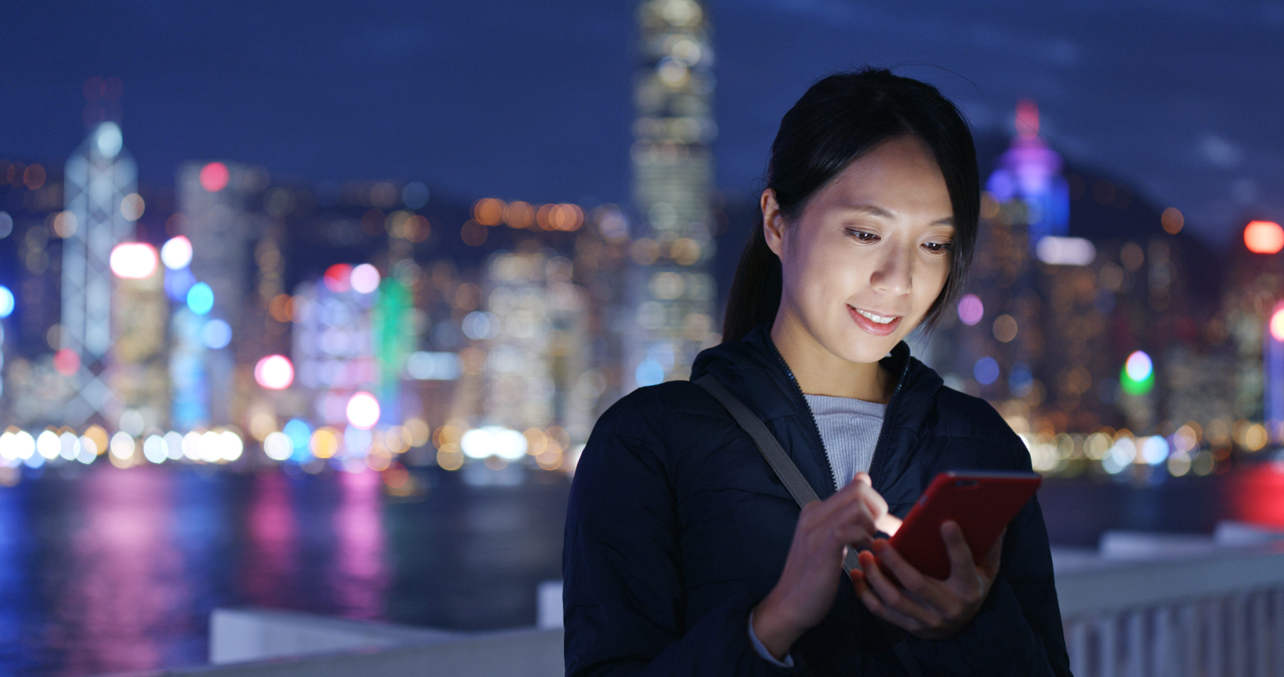 woman-using-mobile-phone-at-night-in-front-of-a-lit-up-city-scape-scaled.jpg