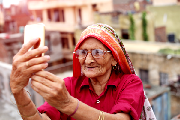 Old-senior-woman-taking-a-selfie-with-holding-smart-phone.png