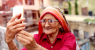 Old-senior-woman-taking-a-selfie-with-holding-smart-phone.png